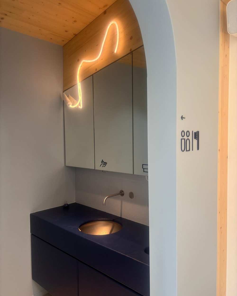 Poetshoek in de praktijk: wastafel in kobaltblauw onder een boog, met neon-tandpasta op de houten wand